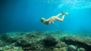 A snorkeller over a shallow reef in clear water